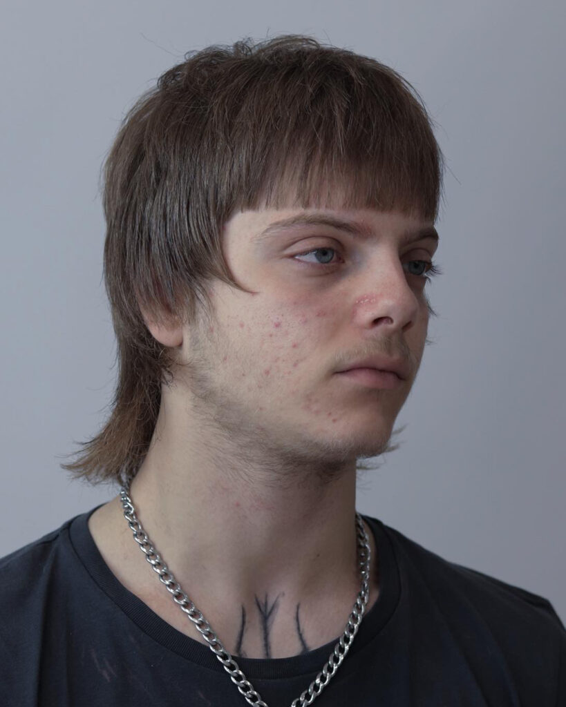 Mullet con frangia netta su capelli castani, vista di tre quarti